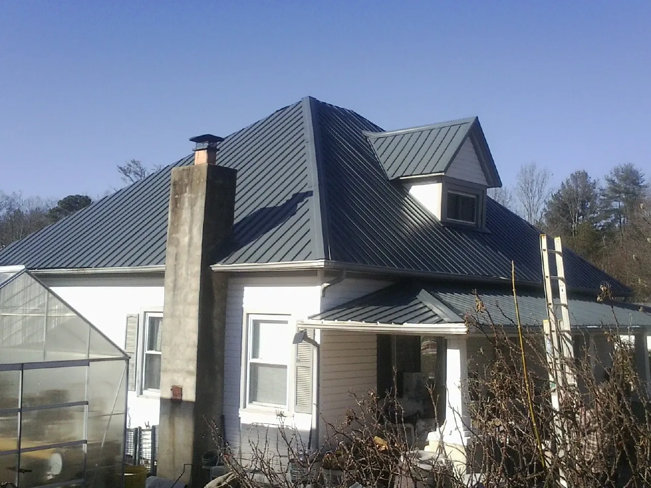 Dark blue standing seam metal roof on a white farmhouse with dormer — Slate & Tile Roof Repair by Roofing Brothers in Shawboro