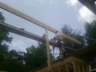 Carpenter setting a ridge beam over a new addition frame — Ice Dam Removal by Roofing Brothers in Shawboro