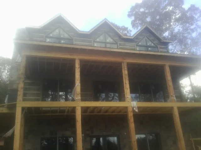 Dormers and porch framing on a large log home under construction — Roof Coating work by our crew in Shawboro