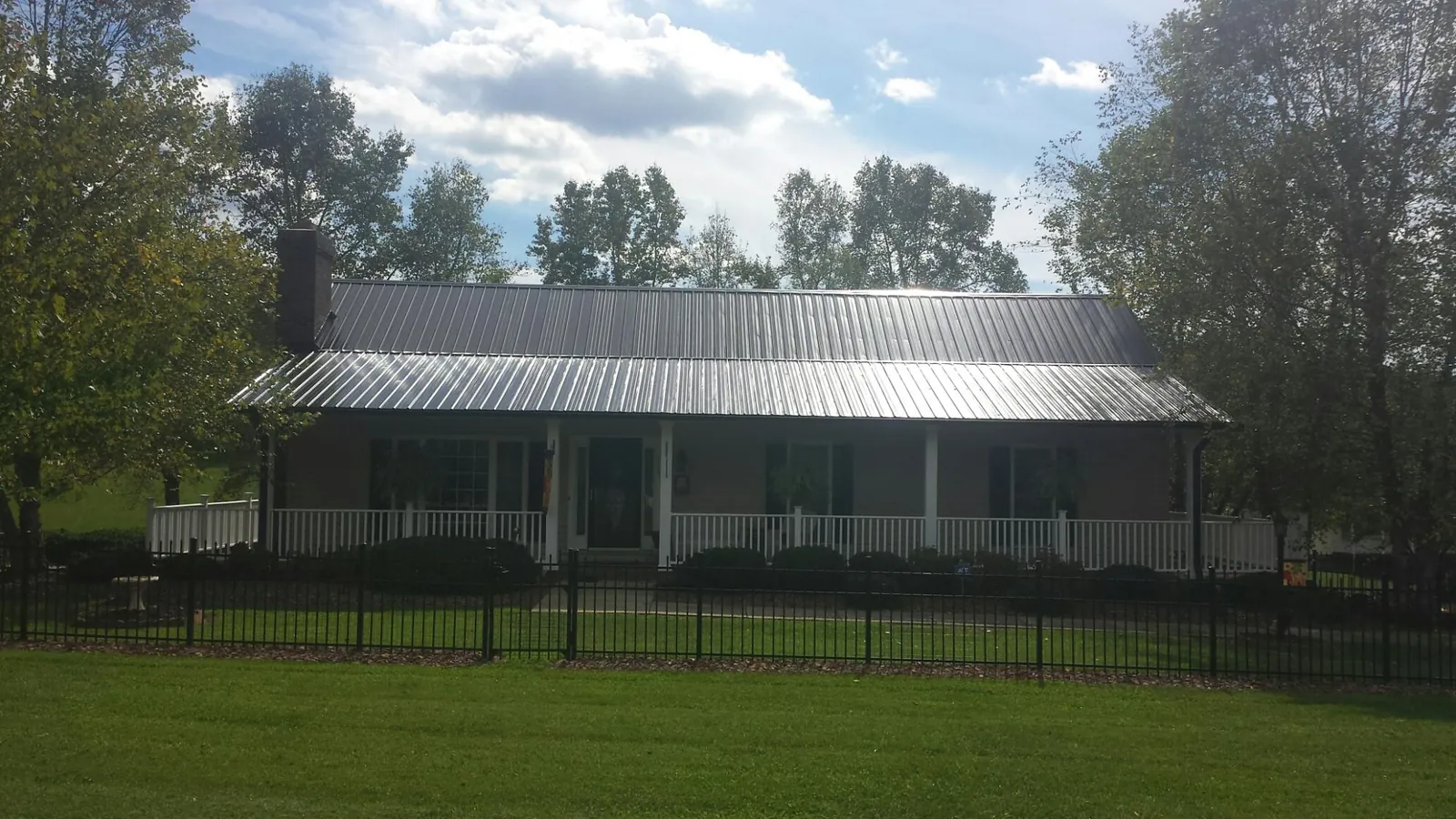 Gray metal roof on a brick ranch with a full width front porch — Gutter Guard Installation work by our crew in Shawboro