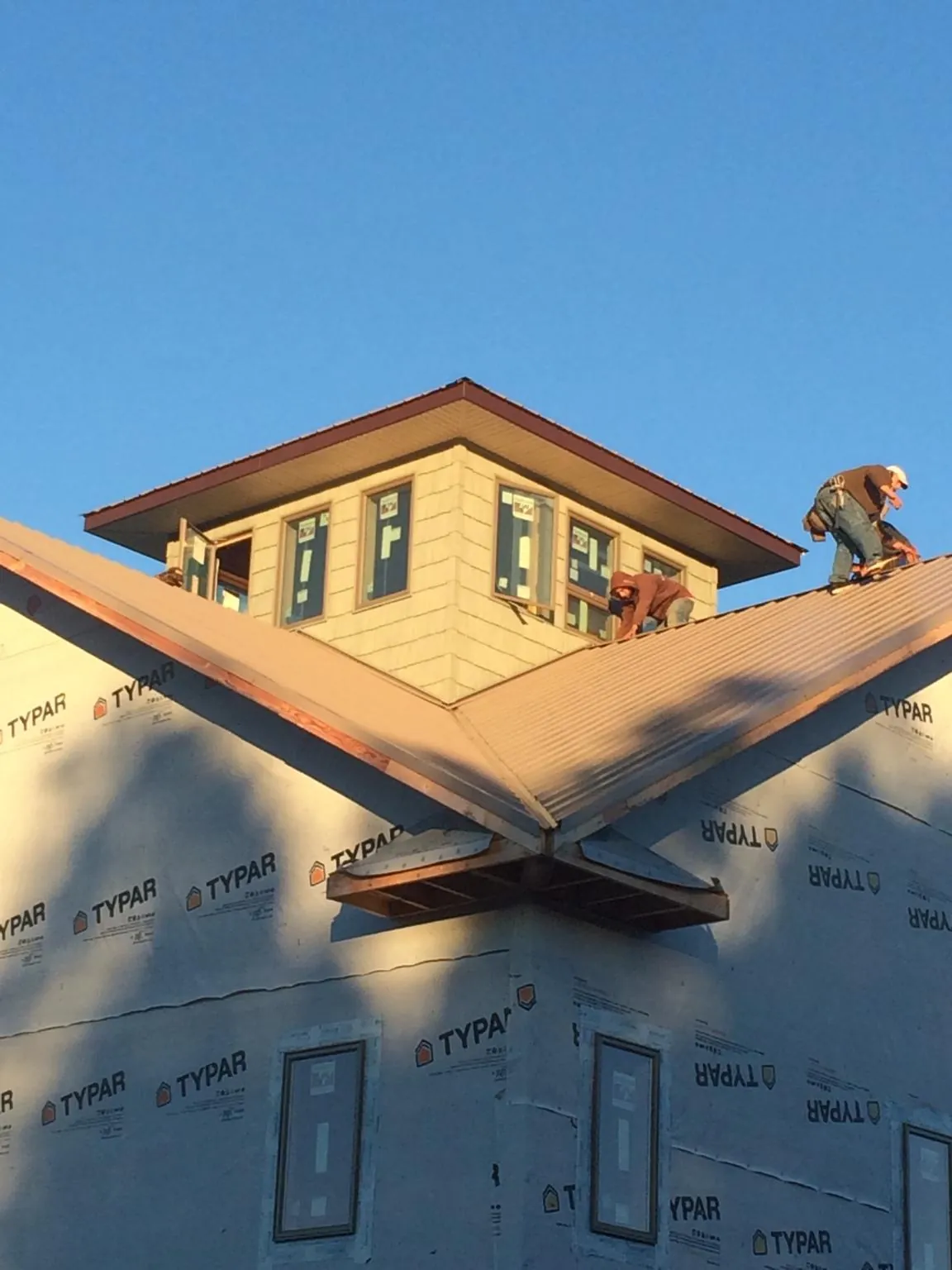 Roofers working around a rooftop cupola on a new metal roof at sunset — Roof Waterproofing in Shawboro by Roofing Brothers